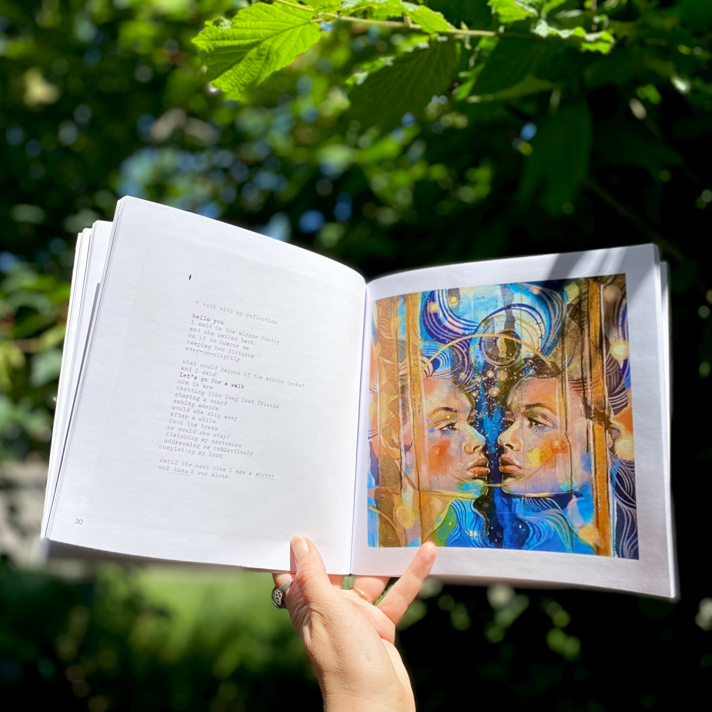 woman's hand holding The Quiet Woman book open on a page showing the poem A Walk With My Reflection alongside the accompanying painting